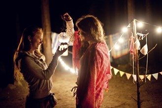 Girls holding lantern at campsite at night