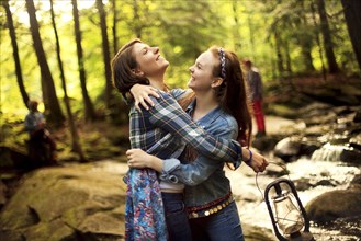 Girls hugging in forest creek