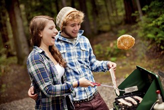 Couple cooking at camp stove in forest