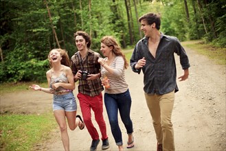 Friends running on dirt path in forest