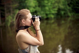 Caucasian teenage girl photographing lake