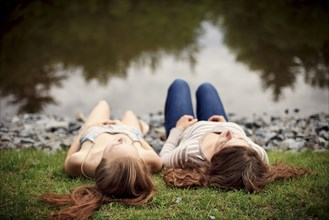 Rear view of girls laying near lake