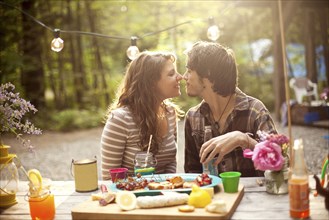 Couple rubbing noses at picnic table in forest