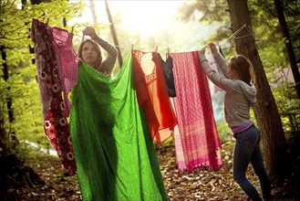 Girls hanging laundry on clothesline in forest