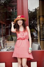 Smiling girl wearing straw hat outside shop