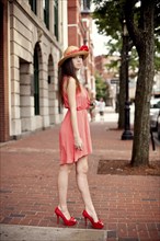 Girl wearing straw hat and high heels on sidewalk