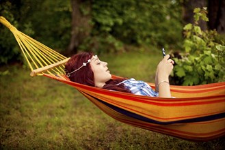 Girl using cell phone and laying in hammock