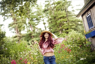 Girl wearing straw hat running in garden