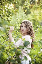Serious woman examining plants in rural field