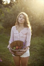 Woman carrying bucket of apples in field