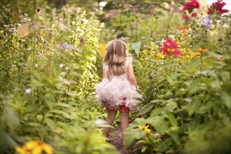Girl in frilly dress exploring tall flowers