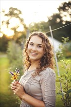 Smiling woman holding flower in garden