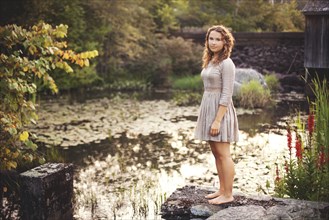 Woman standing on rock overlooking rural pond
