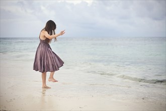 Girl dancing in waves on beach