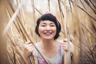 Smiling mixed race woman holding stalks in field