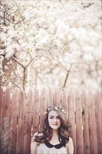 Caucasian teenage girl wearing flower crown near wooden fence