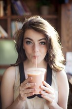 Caucasian teenage girl drinking smoothie in cafe