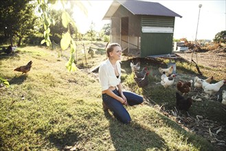 Caucasian farmer crouching by hen house