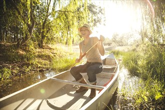 Caucasian woman rowing canoe in rural creek