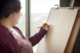 Caucasian artist sketching on easel