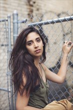 Mixed race woman standing at chain link fence