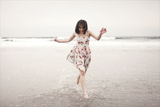 Caucasian woman running in waves on beach
