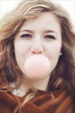 Caucasian teenage girl blowing bubble gum bubble