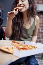 Mixed race woman eating pizza