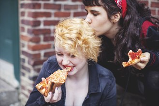 Caucasian women eating pizza outdoors