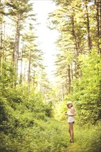 Caucasian woman walking on grass path in forest