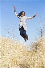 Woman jumping for joy in beach grass