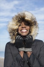 Smiling woman wearing coat on beach
