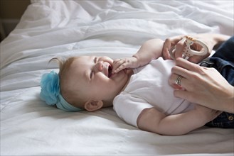 Close up of mother tickling baby girl on bed