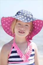 Caucasian girl wearing sun hat and bathing suit on beach