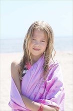 Caucasian girl wrapped in towel on beach