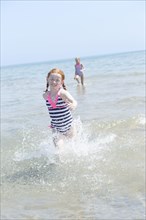 Caucasian girl splashing in waves on beach