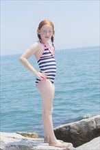Caucasian girl standing on rocks on beach