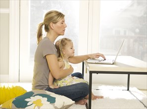 Mother and daughter using laptop in living room