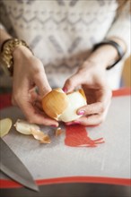 Close up of woman peeling onion on cutting board