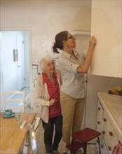 Caregiver reaching in cabinet for older woman