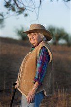 Older Caucasian woman walking with cane in field