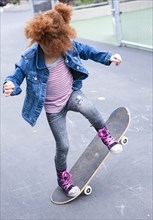 Girl playing with skateboard in urban park