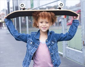 Girl holding skateboard in urban park