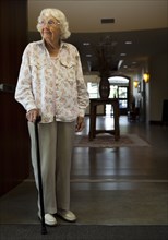 Older Caucasian woman standing with cane in retirement home