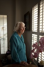 Smiling older Caucasian woman looking out window