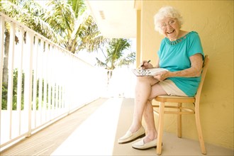 Older Caucasian solving crossword puzzle on balcony