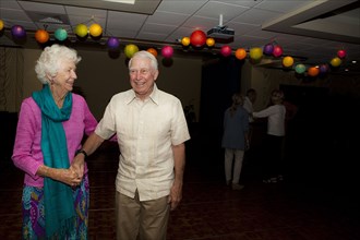 Older Caucasian couple dancing at party in retirement home