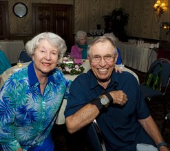Older Caucasian couple smiling at party in retirement home