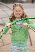 Caucasian girl playing with plastic hoops at playground
