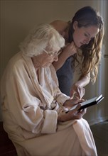 Caucasian caregiver helping older woman use digital tablet
